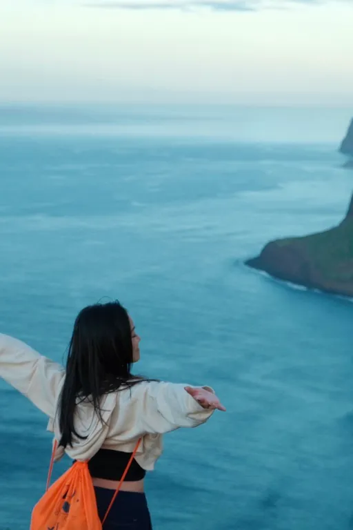 Cristina on a cliff above the sea, arms open