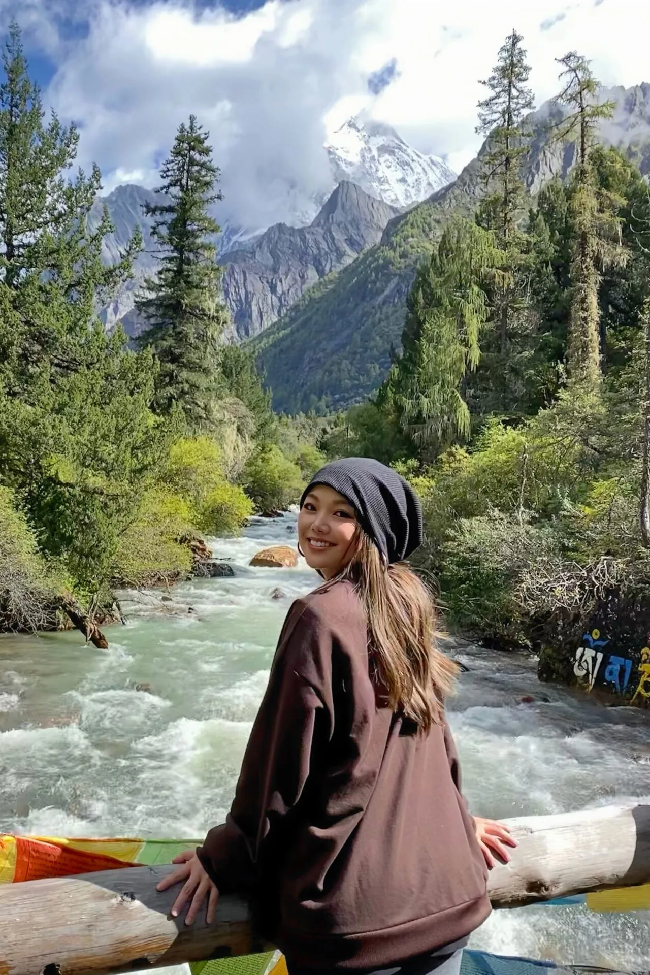 Cristina sitting by a mountain river in a forest