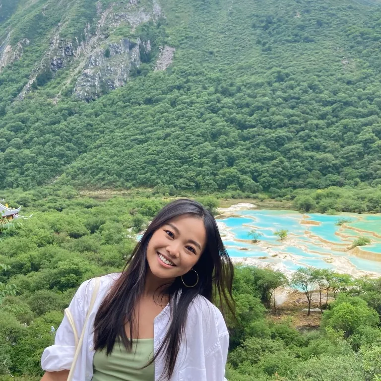 Cristina in front of turquoise terraced pools in a green mountain valley