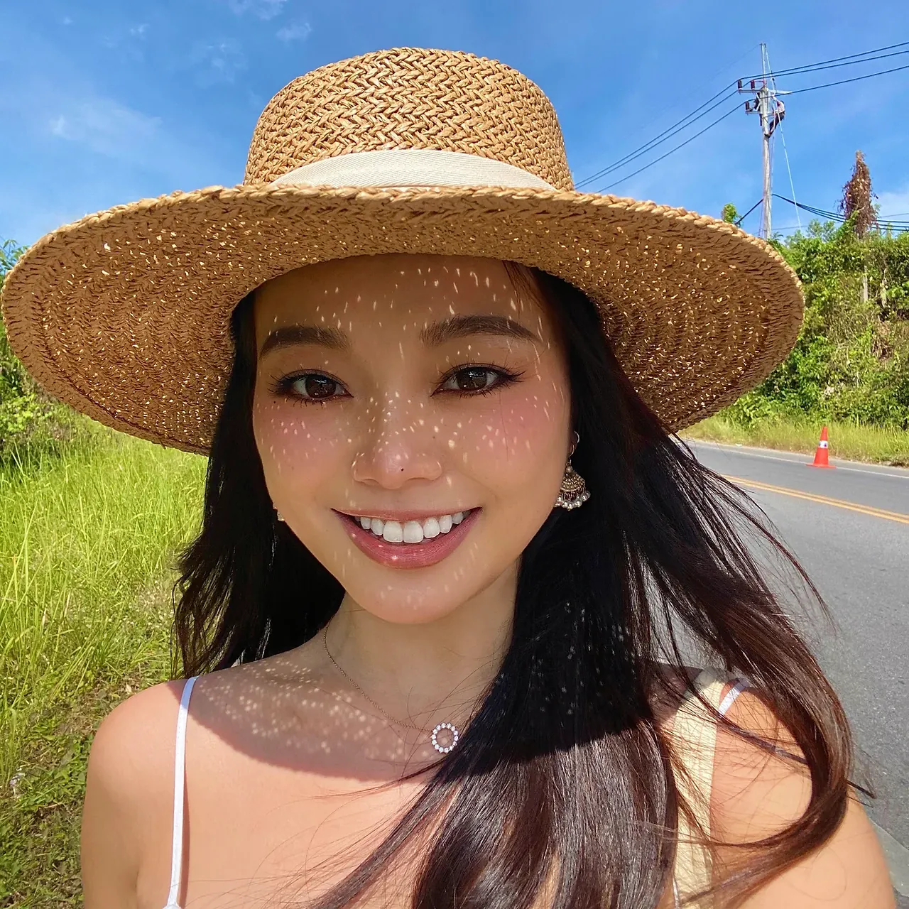 Cristina in a straw hat, smiling in the sun