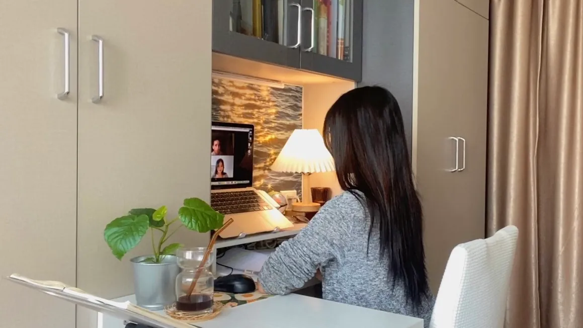 A woman at a computer on a desk at home